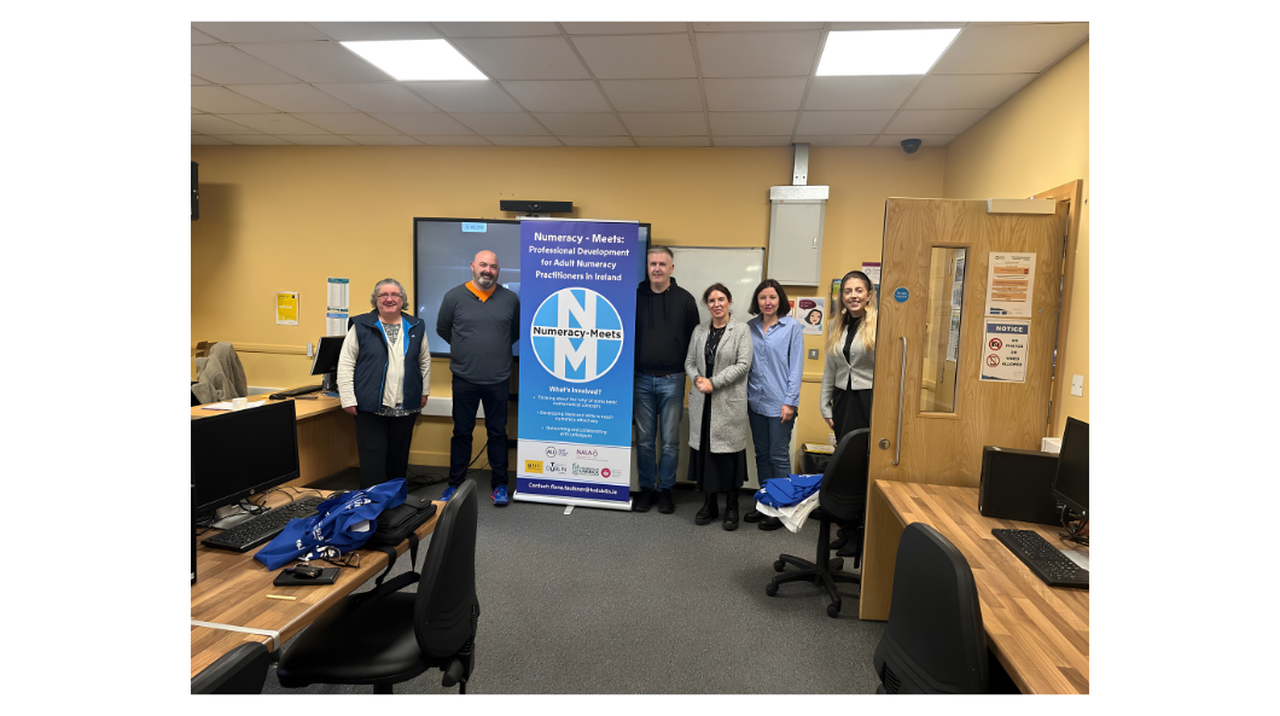 A group of six people standing in a classroom next to a banner titled 